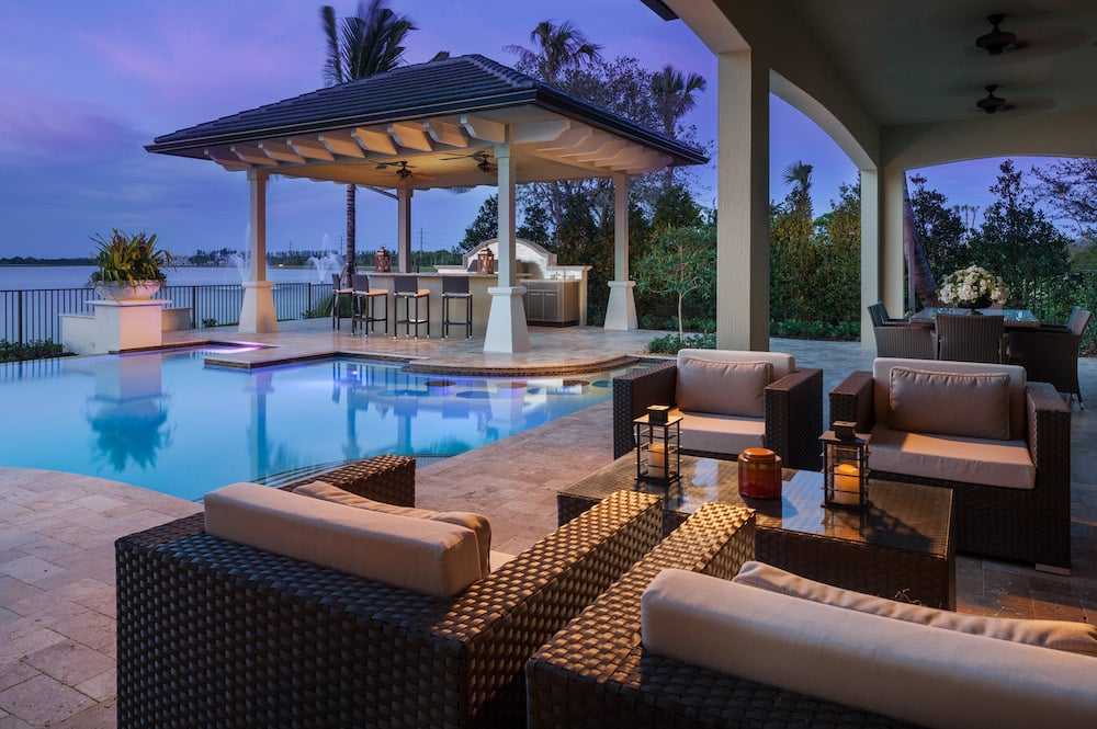 Residential pool lit at dusk with surrounding landscape lighting